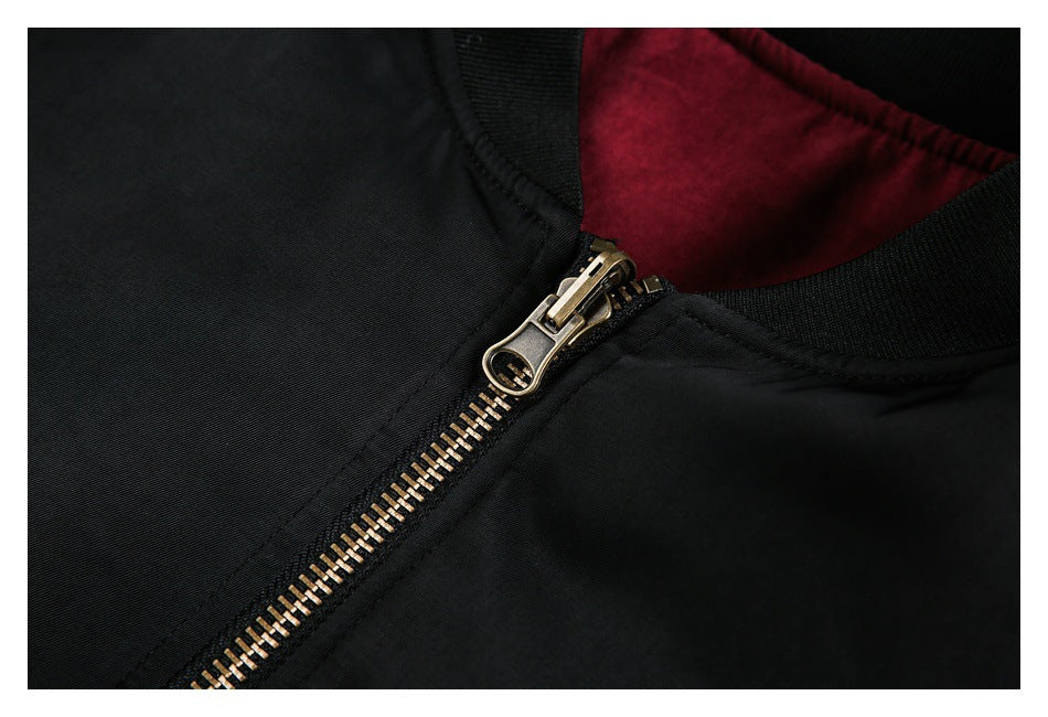 Close-up of the black jacket's brass-tone zipper, ribbed collar, and burgundy lining.