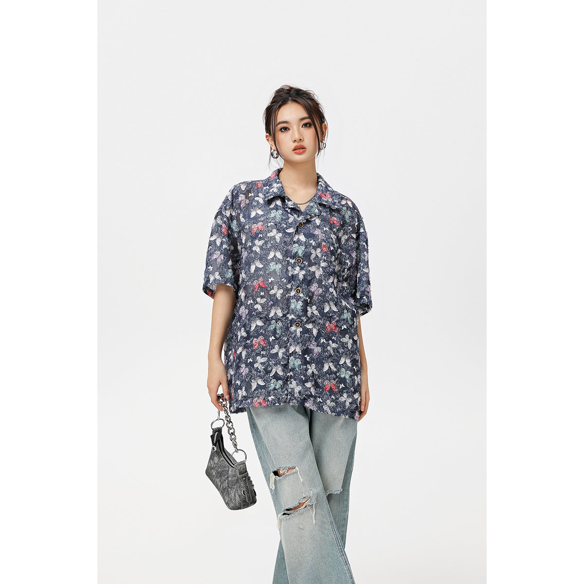 Front view of a model in an oversized navy short-sleeve button-up shirt with a multicolor butterfly print.