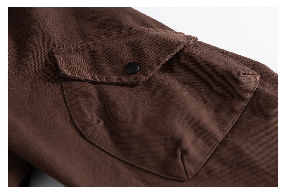 Close-up of a dark brown jacket's flap pocket with a black snap button.