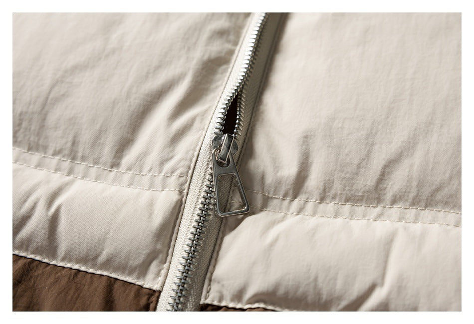 Close-up of a silver zipper crossing the cream panel of a color-blocked jacket.