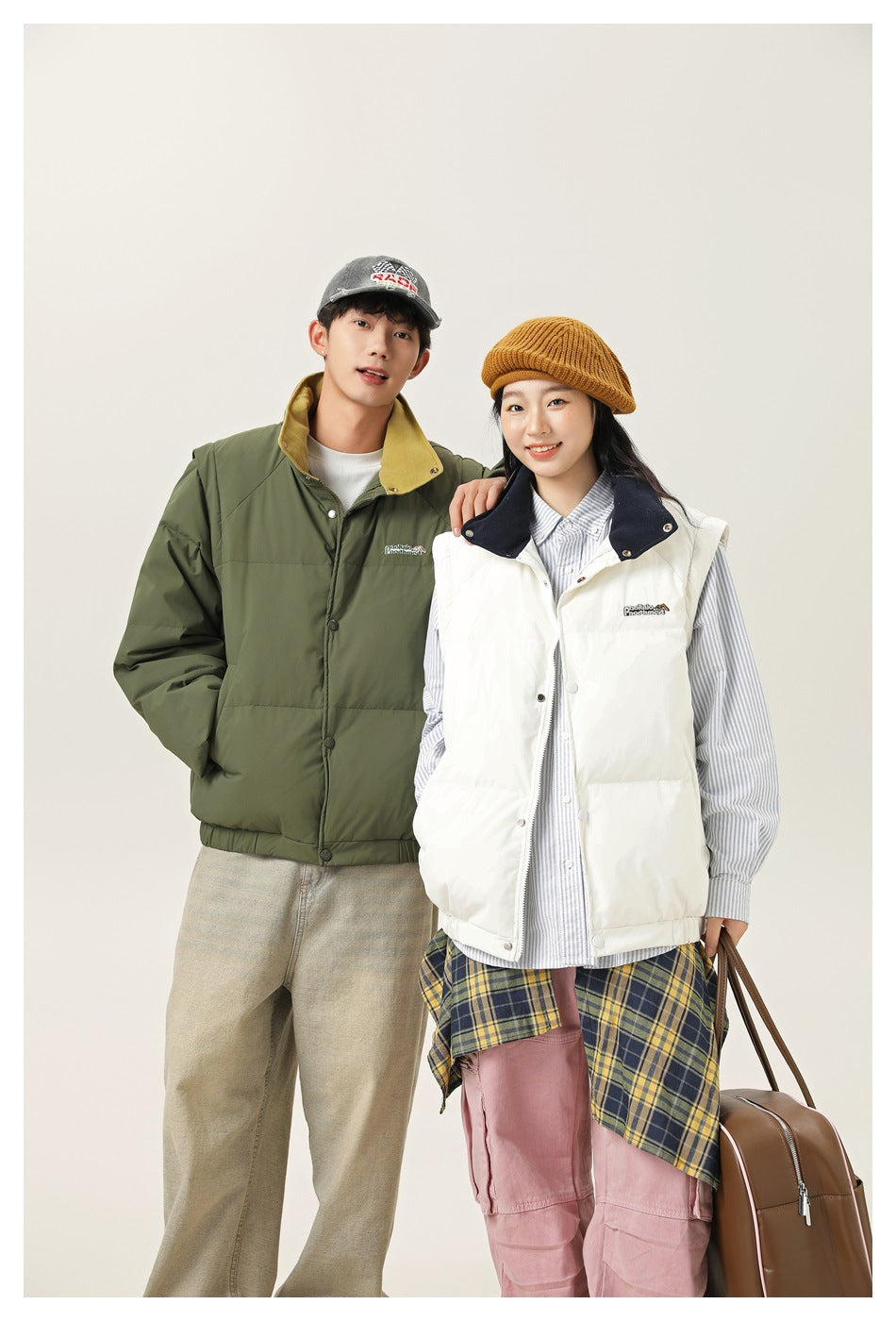 Two models pose together in an olive padded jacket and a white padded vest with a navy collar.