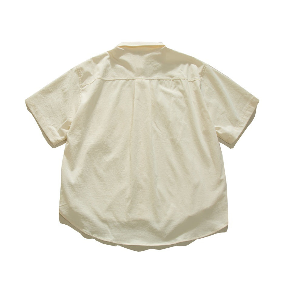 Back view of off-white short-sleeve shirt showing back yoke and center pleat, flat lay