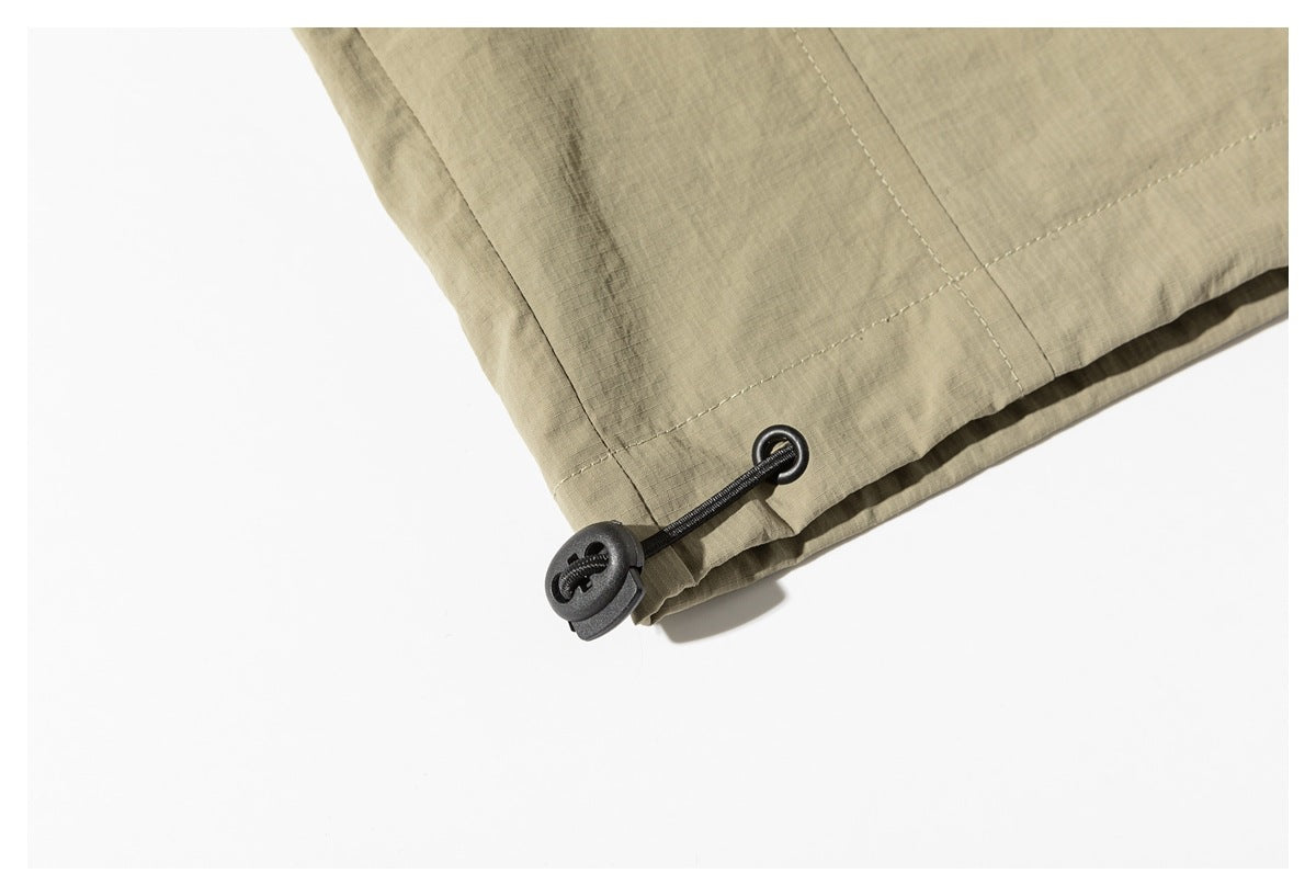 Close-up of a khaki jacket hem with a black elastic drawcord and toggle.
