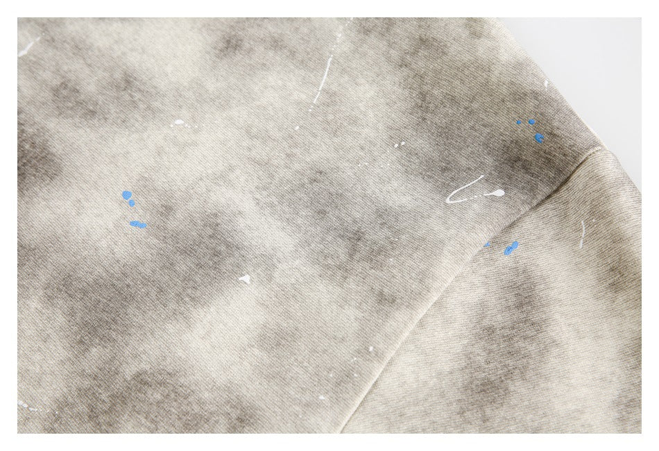 Close-up of the beige-gray shirt's mottled pattern, scattered white and blue marks, and sleeve seam.