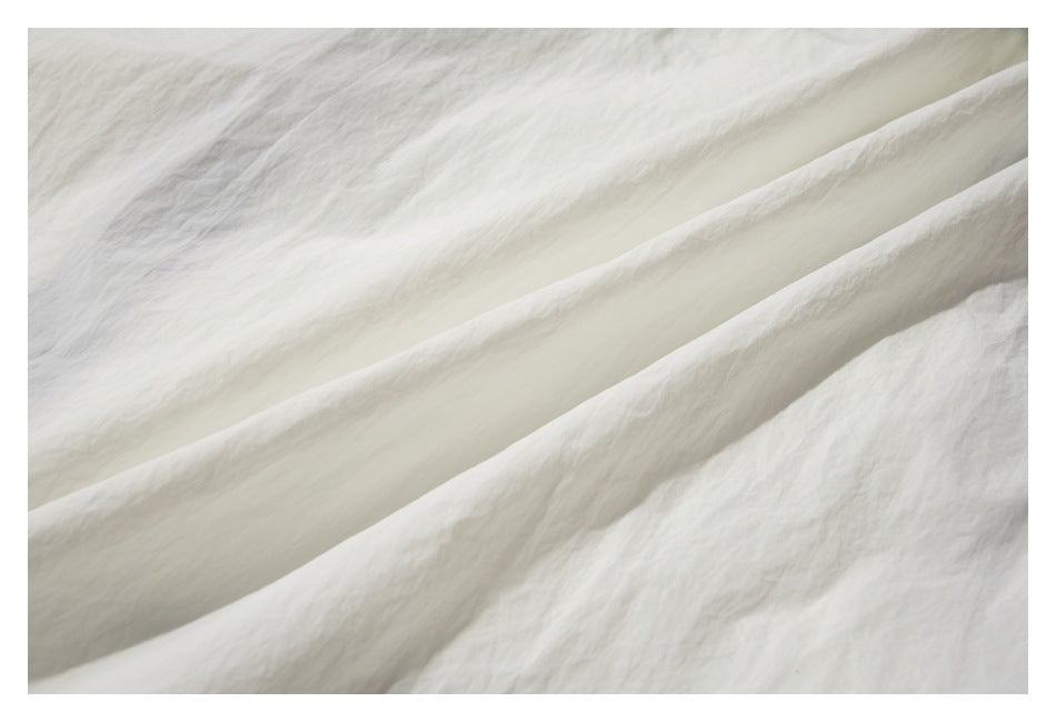 Close-up of softly folded, lightly textured off-white fabric.