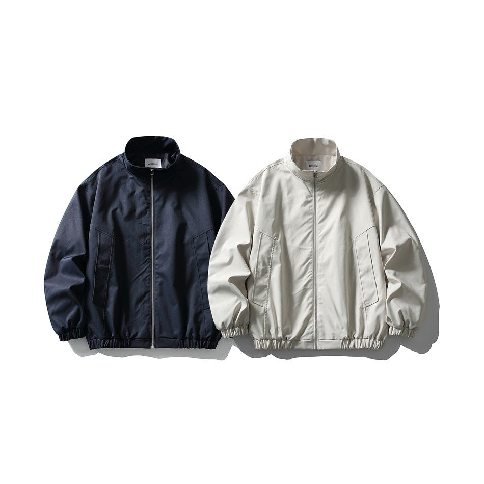 Front view of two zip-up jackets with stand collars and gathered cuffs and hems, in navy and off-white.