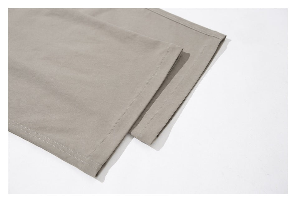 Close-up of taupe-gray trouser legs and stitched hems laid flat on a white surface.