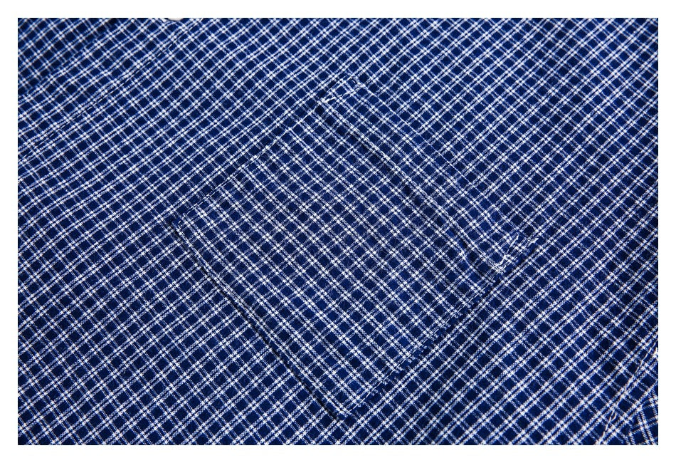 Close-up of a navy-and-white checked shirt showing a stitched chest pocket.