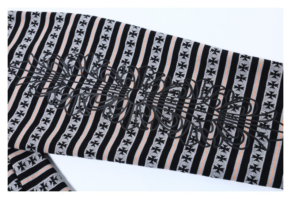 Close-up of a sleeve area with black ornamental artwork over gray and black stripes with peach accents.
