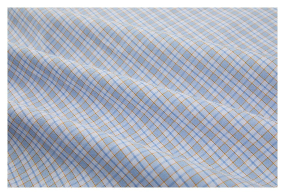 Close-up of light blue fabric with a fine tan-and-blue grid pattern, softly draped.