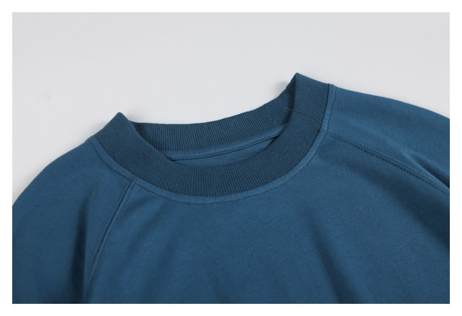 Close-up of a blue sweatshirt's ribbed crew neck and raglan shoulder seams.