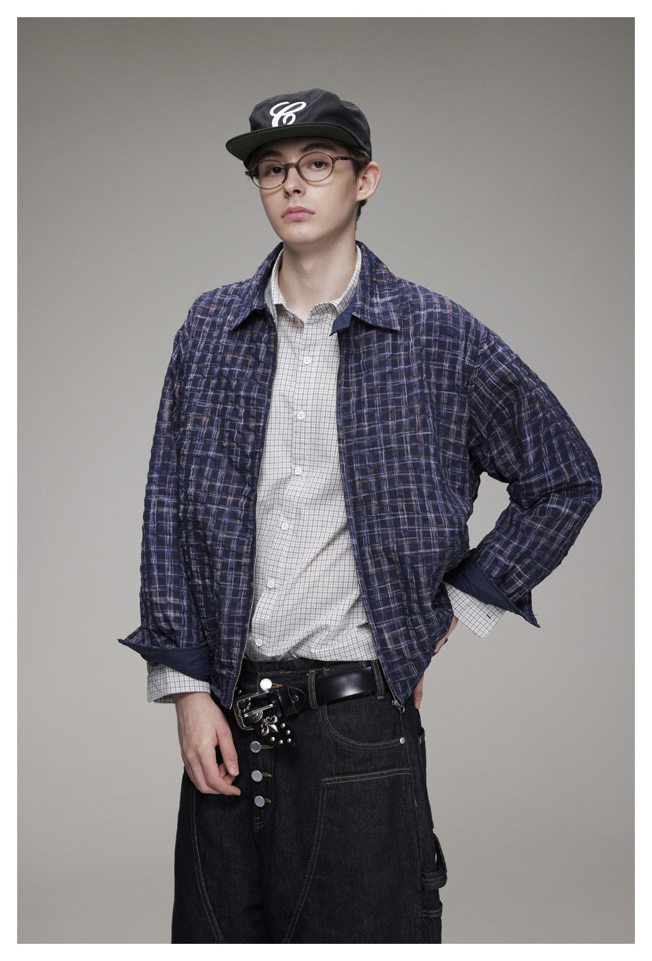 Closer front view of a model wearing a navy plaid jacket over a light checked shirt.