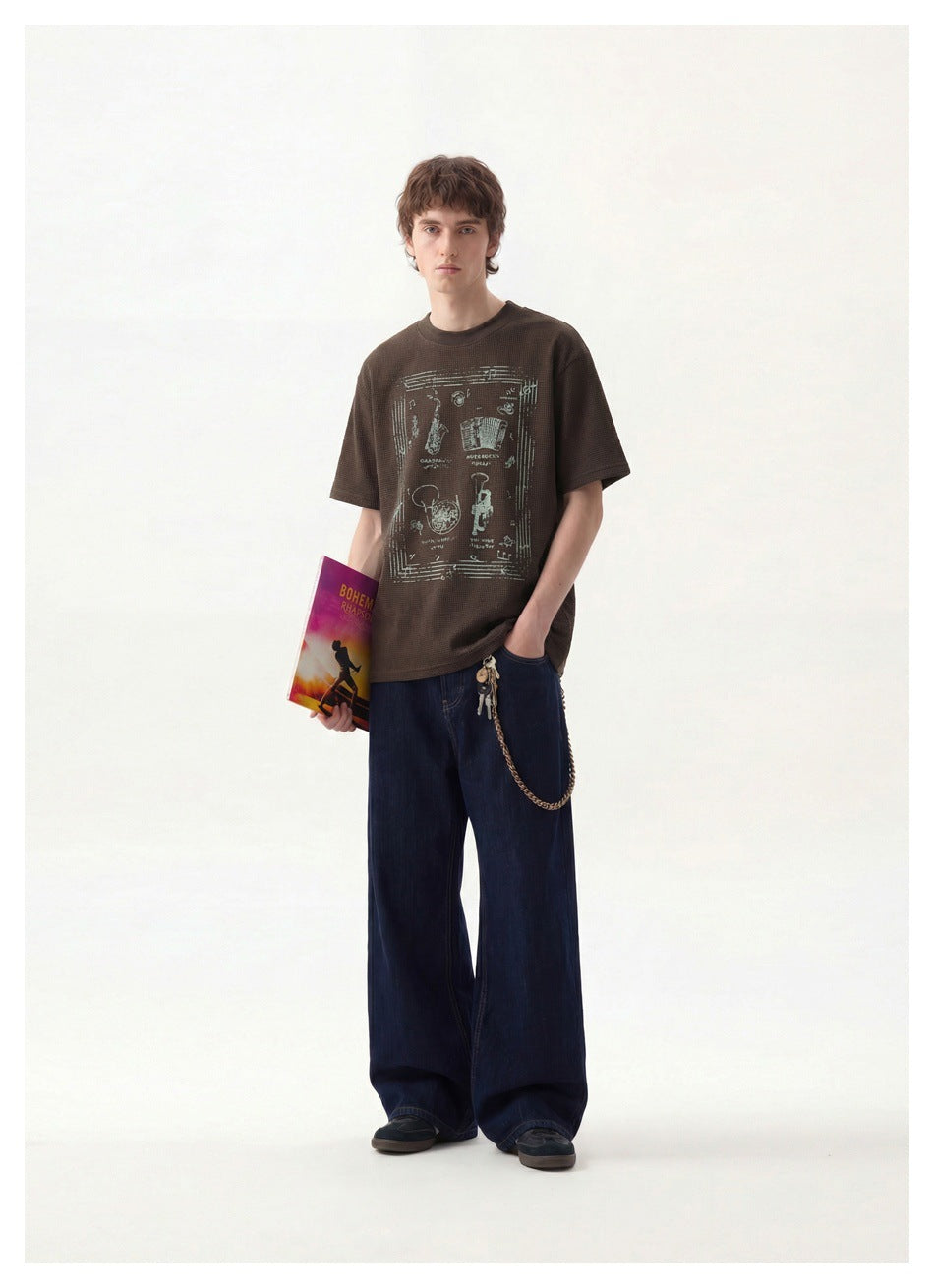 Model wearing a dark brown graphic T-shirt with dark blue wide-leg jeans, shown from the front.