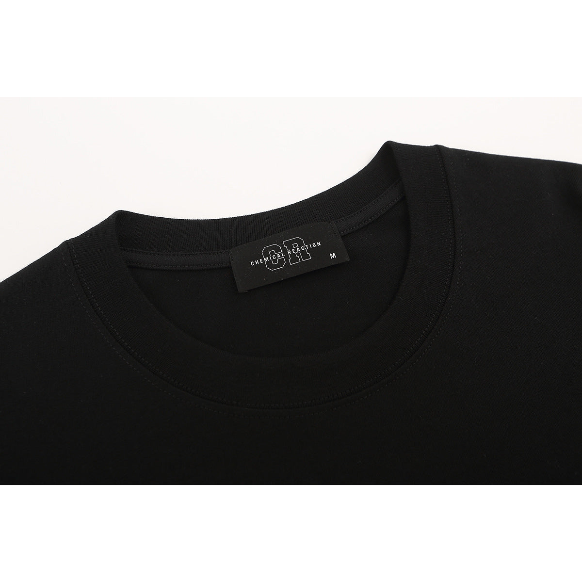 Close-up of a black T-shirt neckline and ribbed collar, with a visible Chemical Reaction neck label.