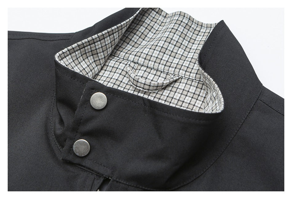 Close-up of a black garment's stand collar, with checked lining and two metal snaps.