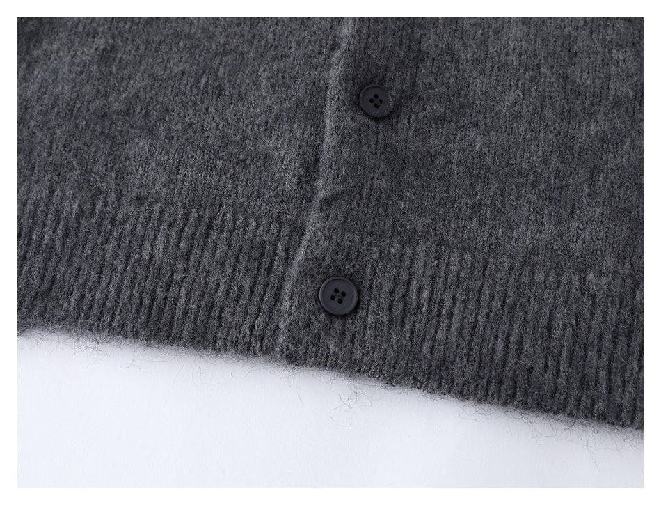Close-up of two dark buttons above the ribbed hem of a charcoal gray cardigan.