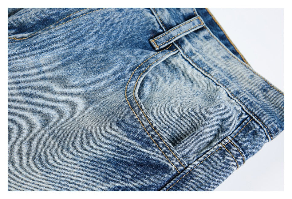Close-up of a front pocket, belt loop, and contrast stitching on the faded blue jeans.