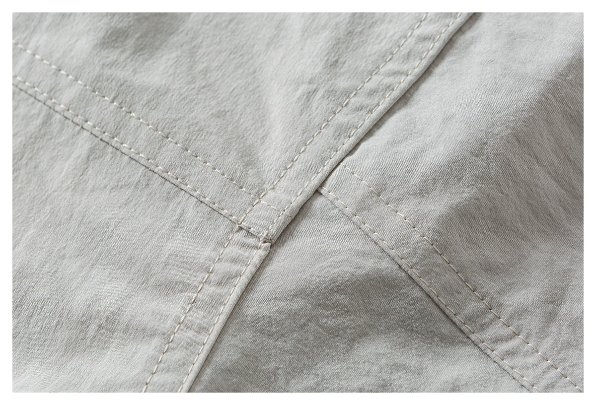 Close-up of overlapping stitched seams on light gray-beige fabric.