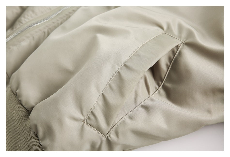 Close-up of a beige jacket's angled hand pocket, ribbed cuff, and part of the front zipper.