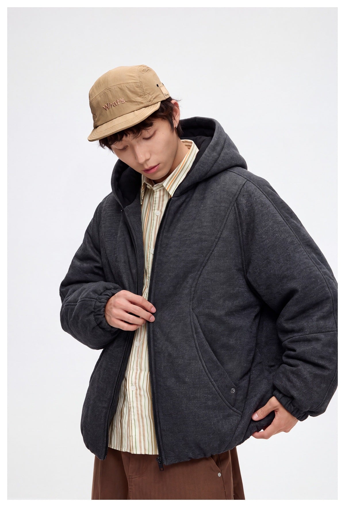 Close front view of a model in a charcoal hooded zip jacket with curved seams and roomy pockets.
