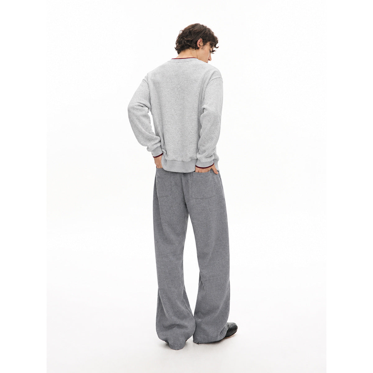 Rear view of a model wearing a light gray sweatshirt and wide-leg dark gray pants with back pockets.