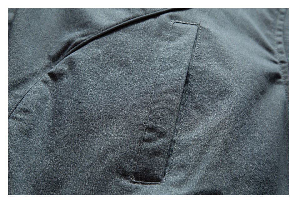 Close-up of a vertical welt pocket on dark charcoal jacket fabric.