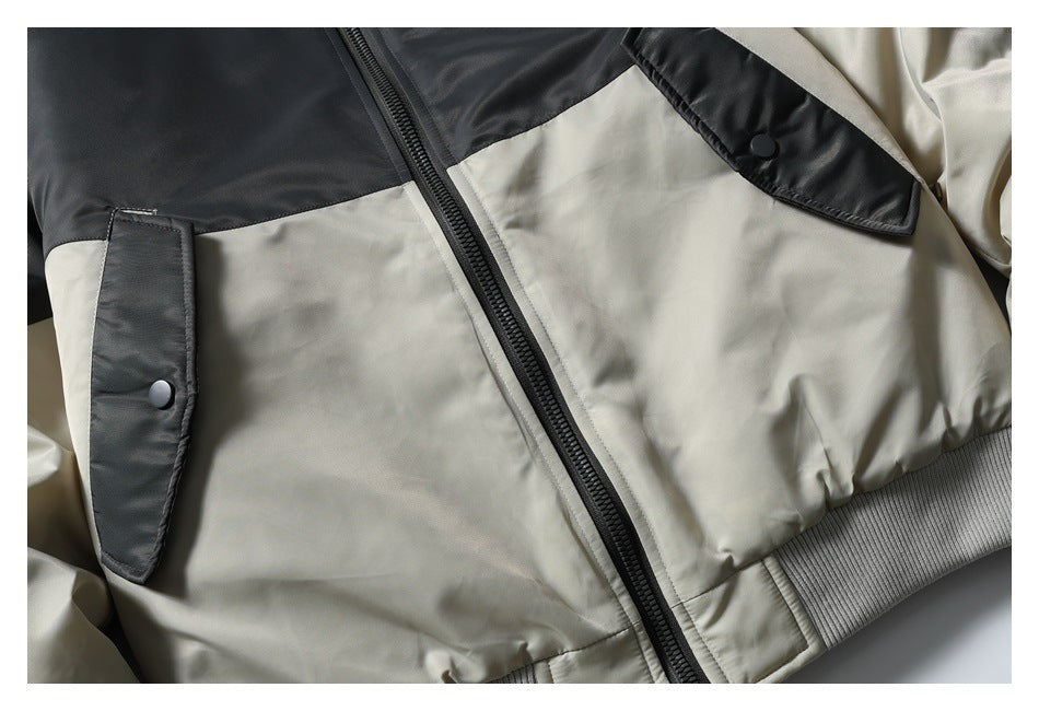 Close-up of the jacket's black zipper, beige body panels, snap pockets, and ribbed hem.