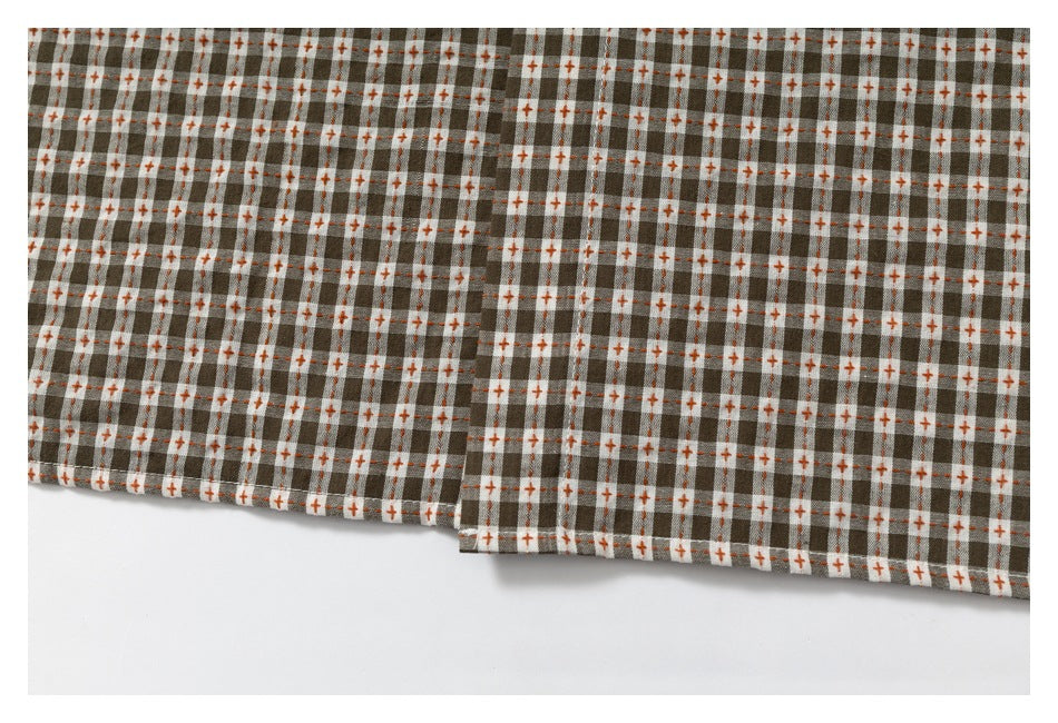 Close-up of the checked shirt hem, showing brown, gray, and cream plaid with orange accents.
