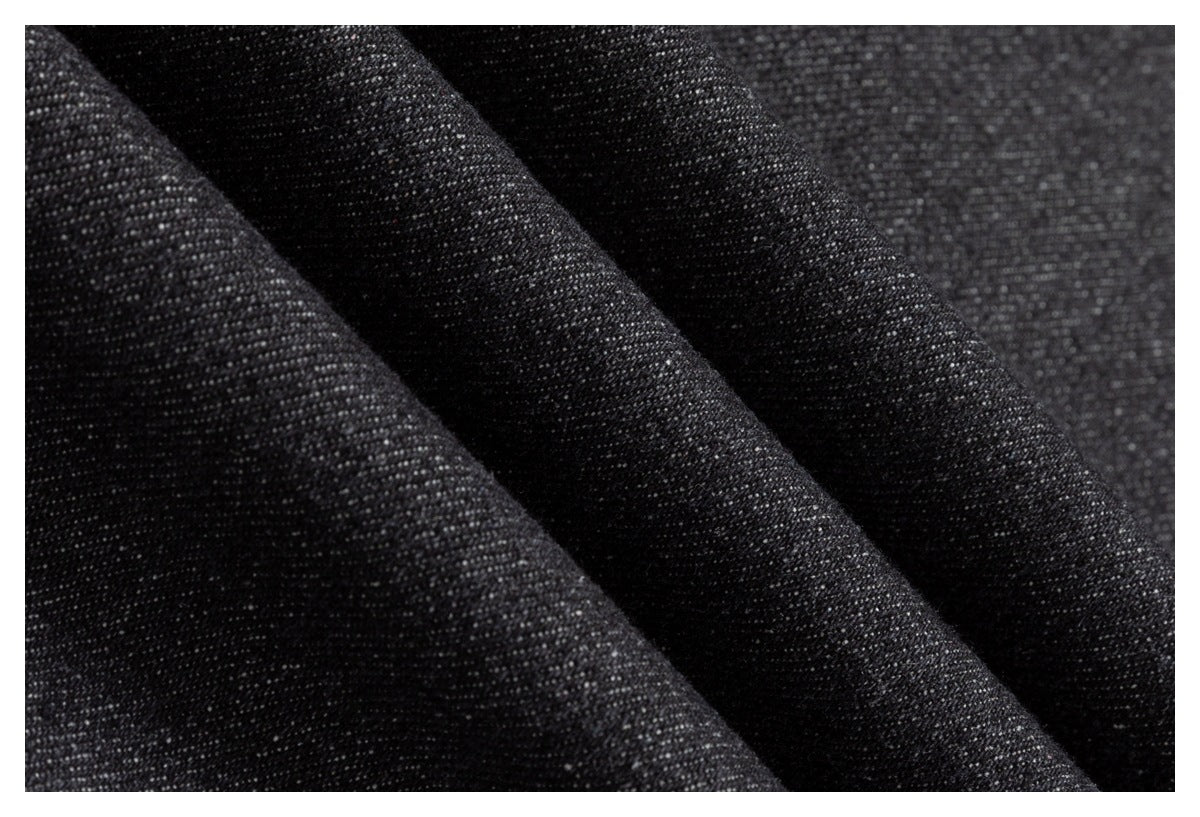 Macro view of dark charcoal denim fabric folded into soft ridges.