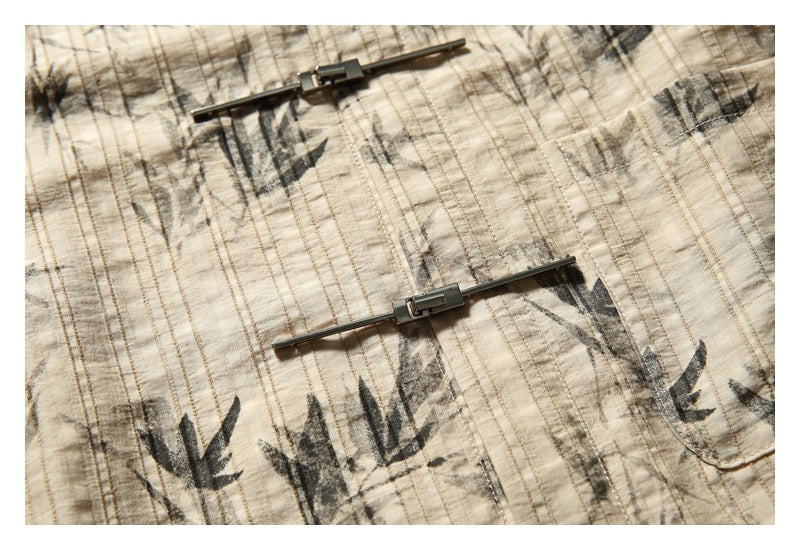 Close-up of two metal bar fasteners on the beige shirt with dark botanical print and vertical stripe texture.