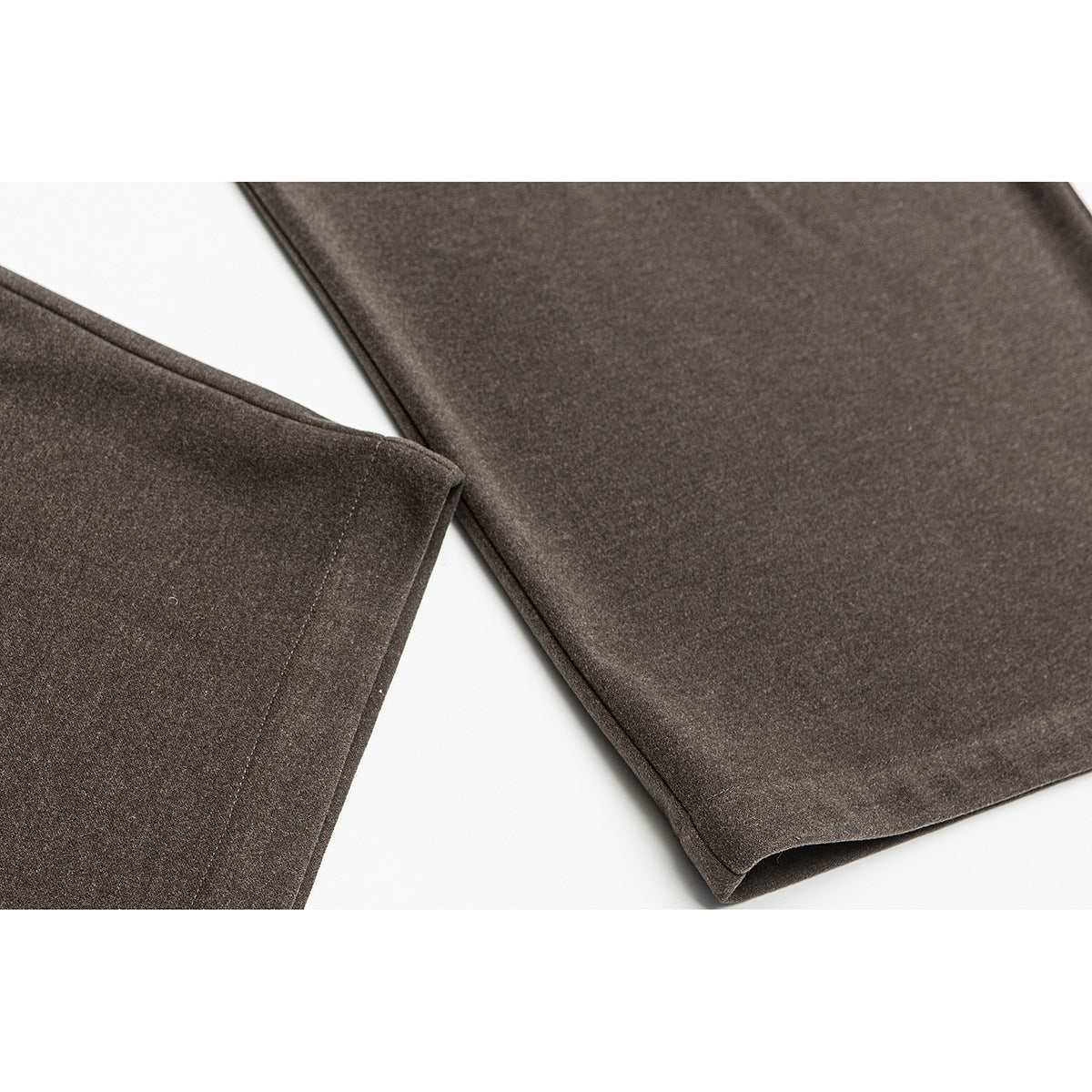 Close-up of brown trouser legs and stitched hems laid against a white background.
