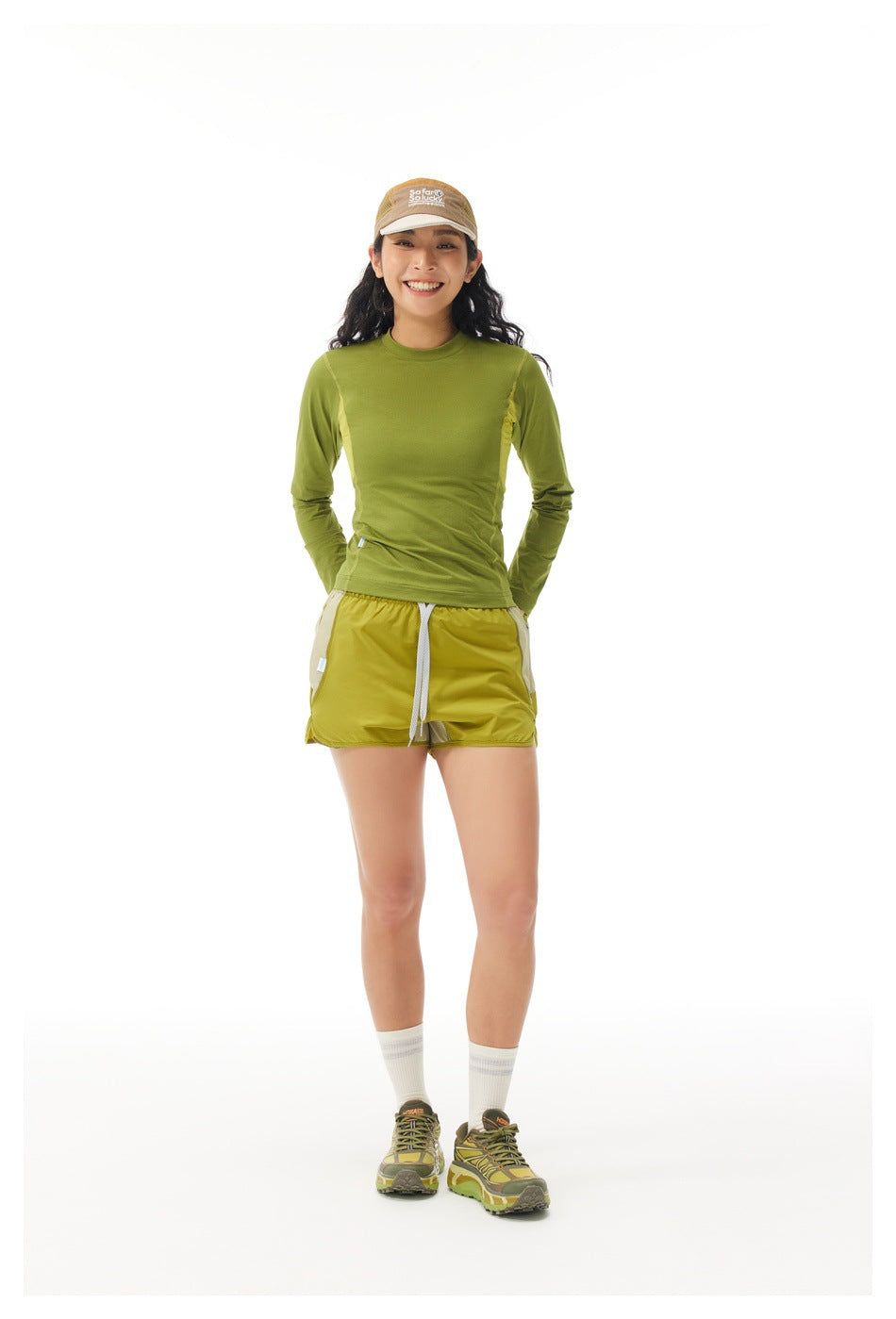 Front view of a model wearing an olive-green long-sleeve top and yellow-green shorts with a white drawstring.