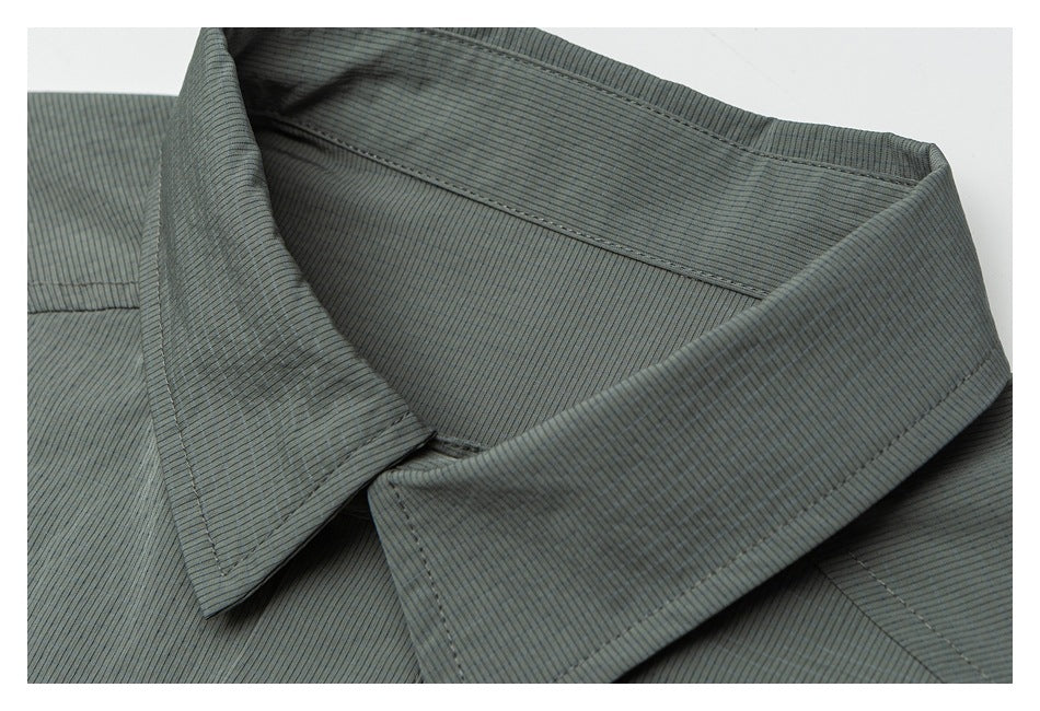 Close-up of a muted gray-green garment's pointed collar, stitching, and fine ribbed texture.