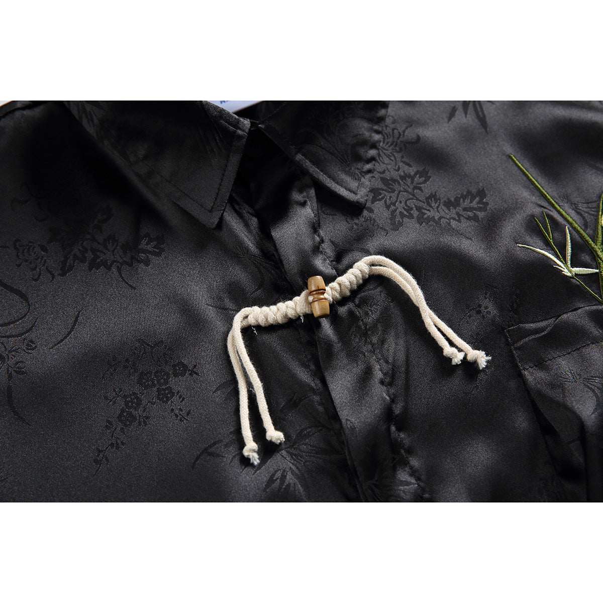 Close-up of a cream rope frog closure with a wooden toggle on black floral-patterned shirt fabric.