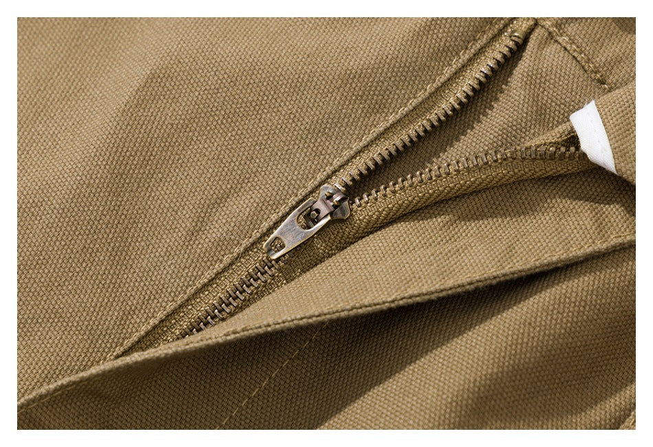 Extreme close-up of the tan shorts' metal zipper and surrounding fabric.