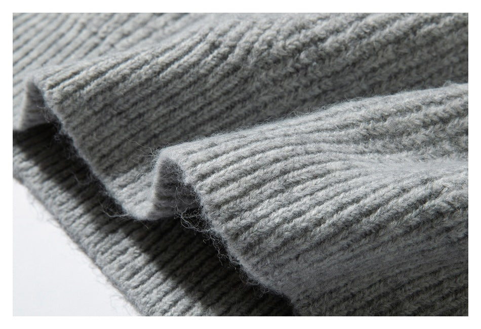 Close-up of ribbed edges and textured knit on a light gray garment.