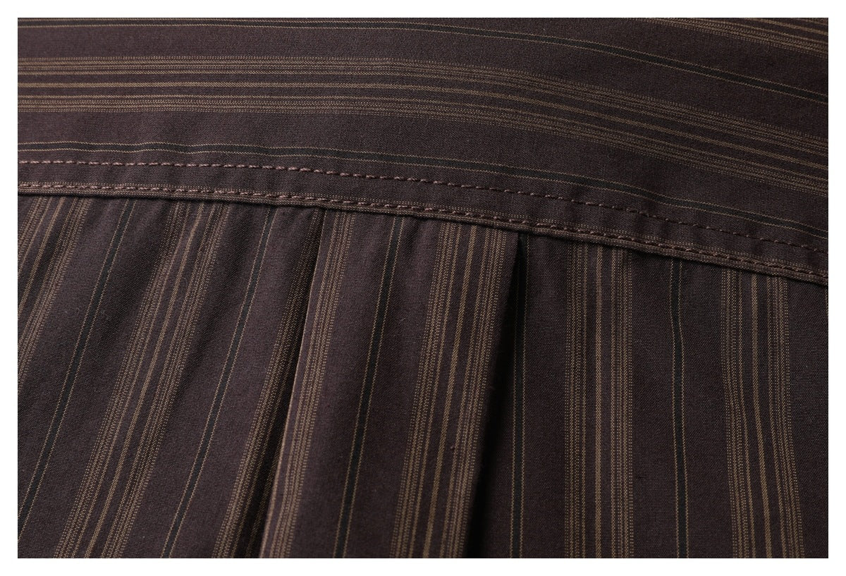 Close-up of a stitched seam and pleats on dark brown fabric with fine tan stripes.