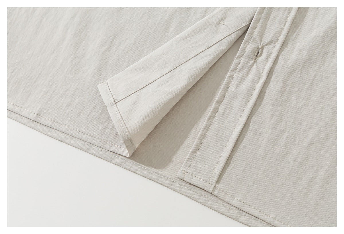 Close-up of the off-white shirt's hem and placket stitching, with one panel folded back.