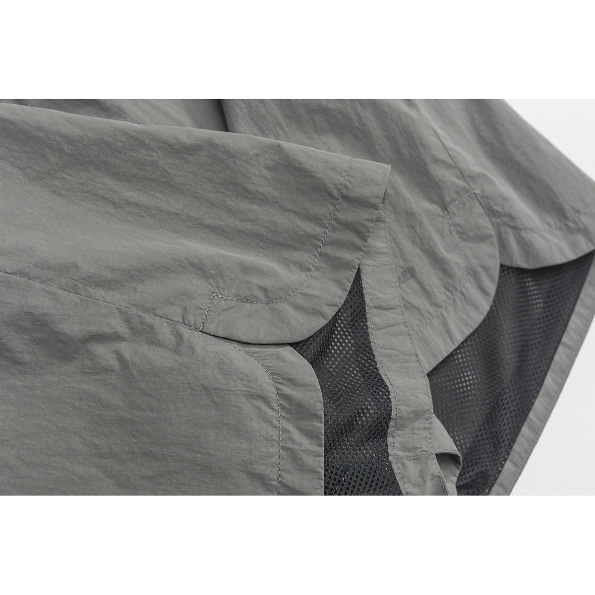 Close-up of gray shorts showing the hem, stitching, and black mesh lining.