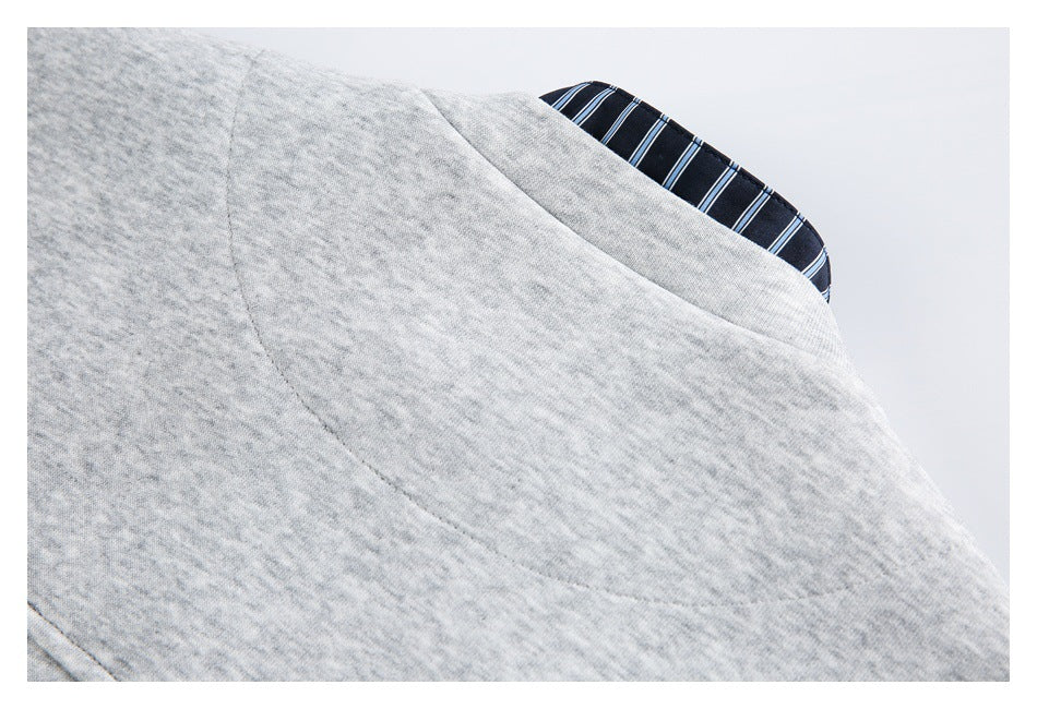 Close-up of a light gray heather garment seam with a glimpse of navy blue-and-white striped lining.