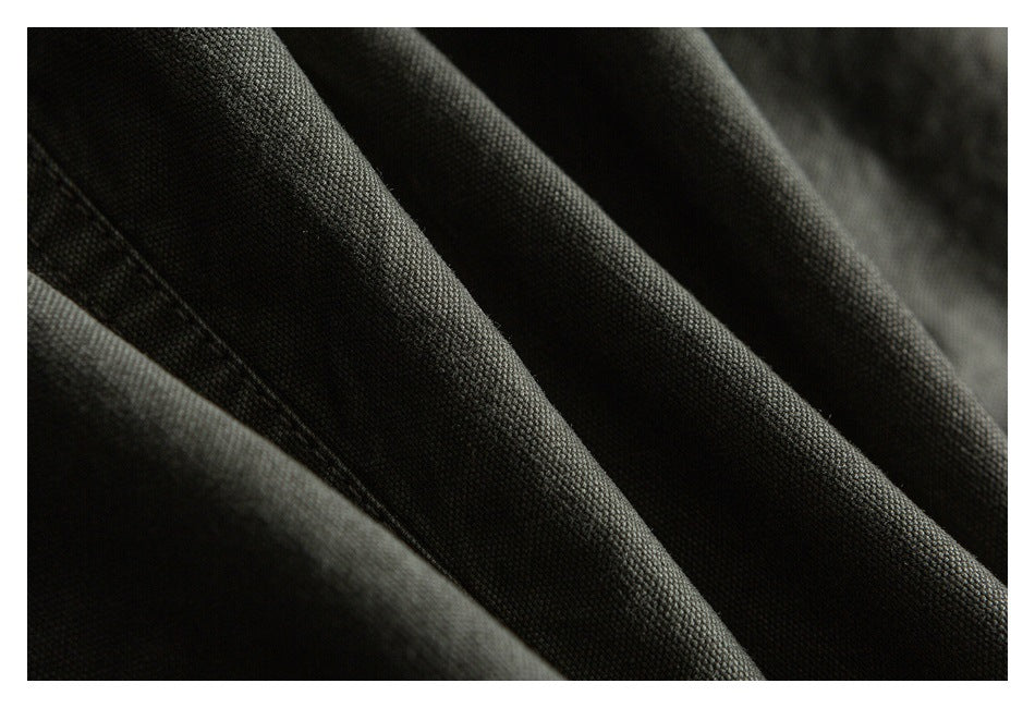 Close-up showing the dark olive garment's woven fabric texture and stitched seam.