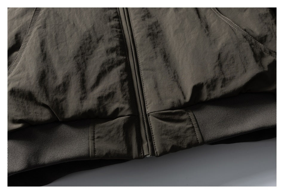 Close-up of the jacket's center zipper and ribbed lower hem in dark olive and black.