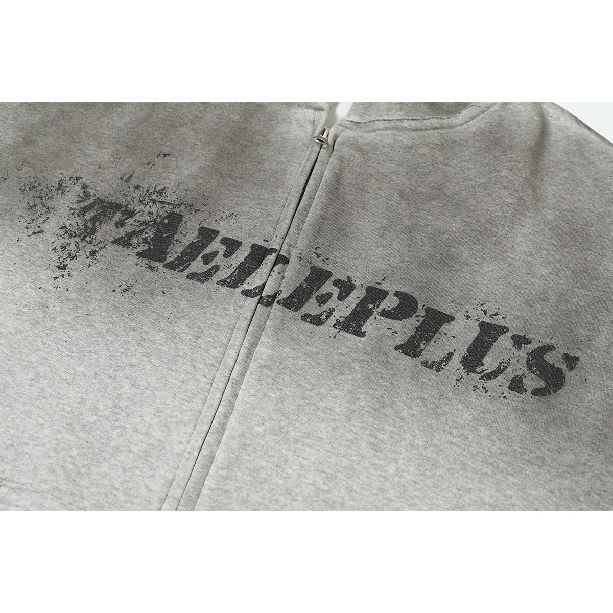 Close-up of distressed black lettering printed across the front of a heather-gray zip-up hoodie.