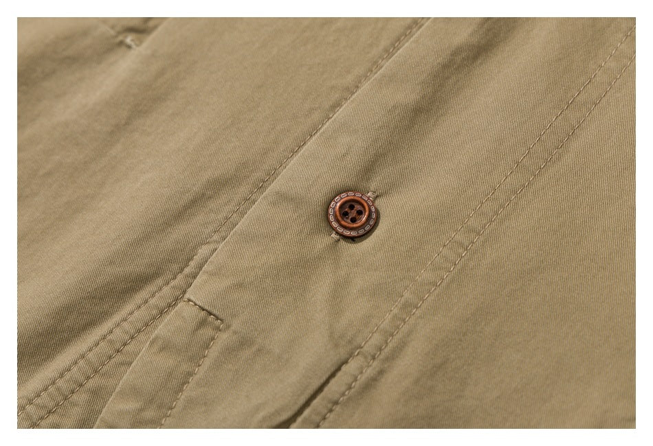 Close-up of a tan garment with a brown button and stitched seam.