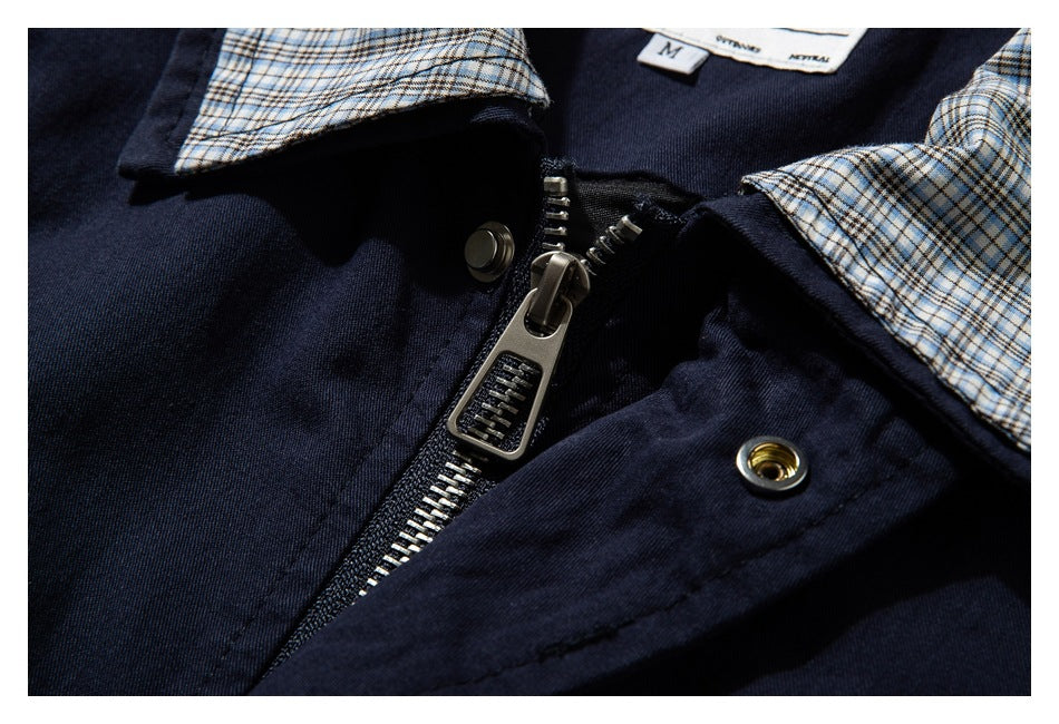 Close-up of the navy jacket's metal zipper and snap fastener beside its beige-and-blue plaid collar lining.