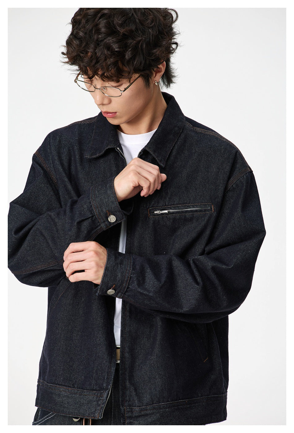 Model in dark denim zip jacket over a white tee, adjusting the buttoned cuff, close-up