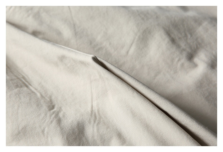 Close-up of the light beige trouser fabric folded to show its surface and edge.