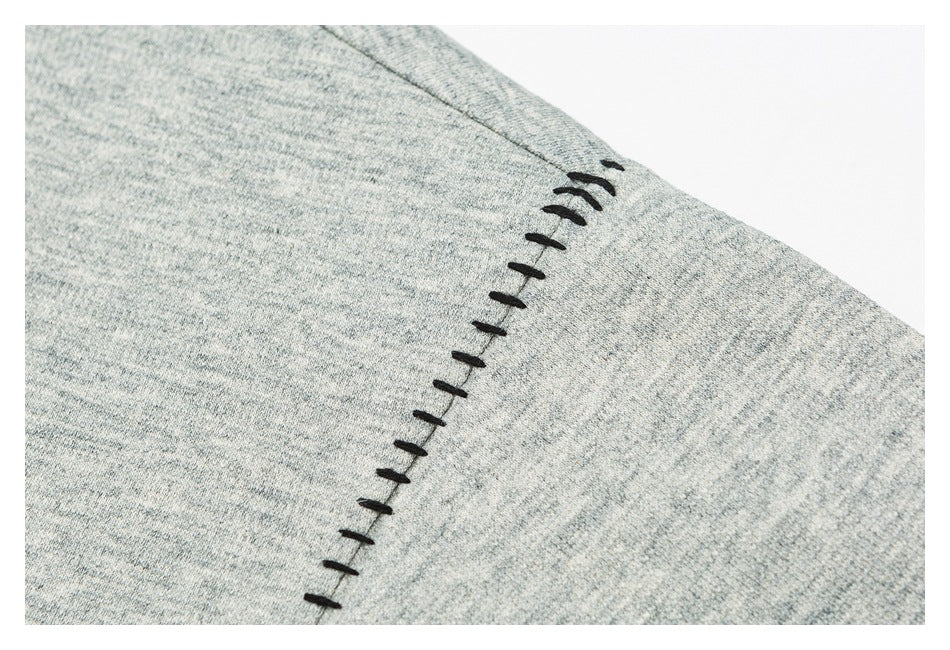 Close-up of black decorative stitch accents along a seam on heather-gray fabric.