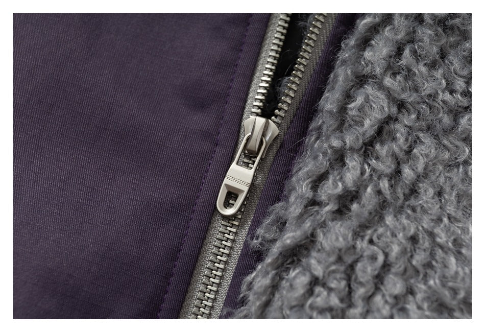 Close-up of a gray metal zipper beside curly gray fleece lining on dark plum fabric.