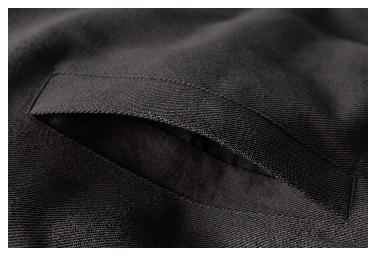 Close-up of a stitched pocket opening on dark charcoal fabric.
